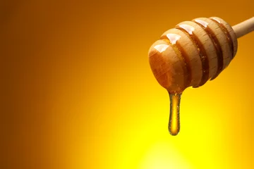 Foto op Aluminium Pouring honey from dipper against golden background, space for text © New Africa