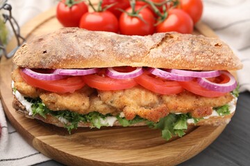 Delicious sandwich with schnitzel on grey wooden table, closeup