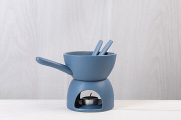 Fondue set on white wooden table. Kitchen equipment