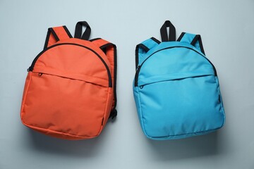 Stylish backpacks on light grey background, flat lay