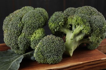 Wooden board with fresh raw broccoli on table, closeup.