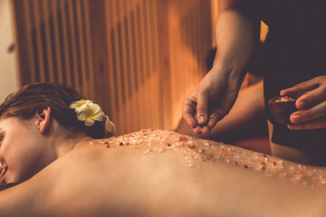 Closeup couple customer having exfoliation treatment in luxury spa salon with warmth candle light ambient. Salt scrub beauty treatment in Health spa body scrub. Quiescent - obrazy, fototapety, plakaty