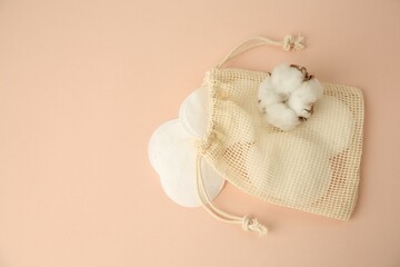 Fototapeta na wymiar Bag with cotton pads and flower on beige background, flat lay. Space for text