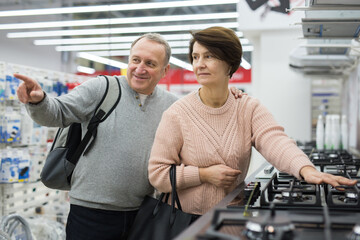 Fototapeta na wymiar Mature couple choose a gas stove in an electronics and home appliance store to buy it