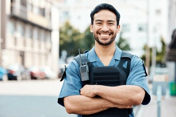 Portrait, happy or policeman in city with arms crossed for law enforcement, surveillance or street safety. Confident cop, smile or proud Asian security guard on patrol in town for crime or justice