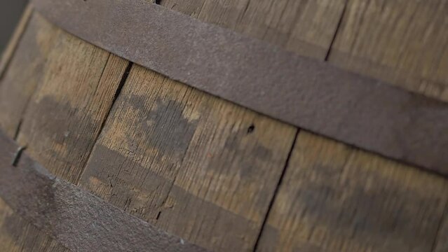 Old wooden wine barrel with iron straps, made of oak, seen on a close up, slow motion camera movement. Aged for decades on a wine house at a traditional winery 