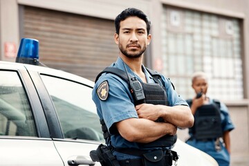 Asian man, police and arms crossed in city for law enforcement, protection or street safety. Portrait of serious male person, security guard or cop ready for justice or crime on patrol in urban town - obrazy, fototapety, plakaty