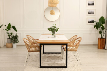 Stylish dining room with cozy furniture, mirror and plants