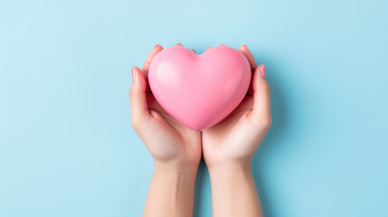Fototapeta premium hands hold a pink heart on a minimal light blue background