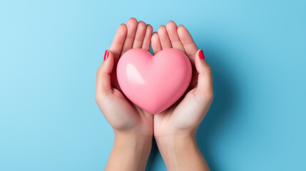 Obraz premium hands hold a pink heart on a minimal light blue background