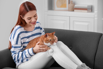 Happy woman with her cute cat on sofa at home