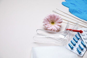 Gynecological tools, pills and gerbera flower on beige background. Space for text