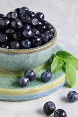 Tasty fresh bilberries in bowl on white table, closeup
