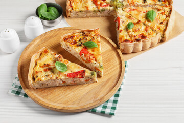 Tasty quiche with tomatoes, basil and cheese on white wooden table