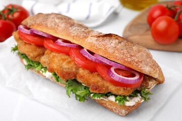 Delicious sandwich with schnitzel on white tiled table, closeup