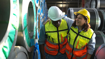 A male factory worker assists a female industrial worker who has an injured leg. As a result of...
