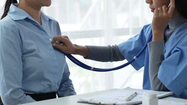 An Asian female doctor uses a stethoscope to listen to the heartbeat of a male patient for guidance in treatment and preventive care. health check concept.	