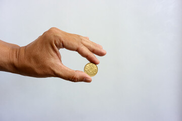 Human hand holding rupiah coin isolated on white background. Collecting, saving, investing or...