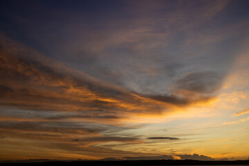 Beautiful sunset with wispy clouds painted in golden colors.