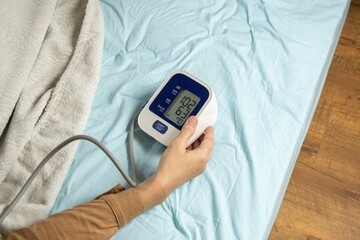 Young woman measuring his blood pressure at home in bed. self blood pressure and heart rate