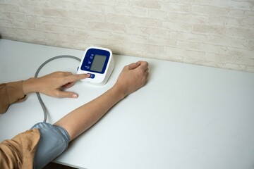 Young woman measuring his blood pressure at home. self blood pressure and heart rate