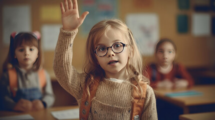 A little girl kid in school classroom raising hand up to answer teacher.