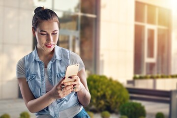 Pretty woman use smartphone against building.