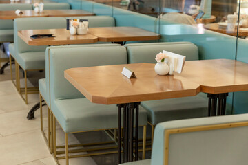 Wooden tables with turquoise sofas in a cozy cafe.