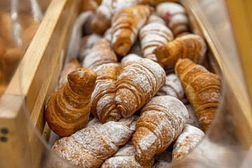 Croissants with powdered sugar in the store. Appetizing pastries, morning ritual. Close-up.