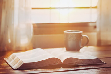 close up of an open bible with a cup of coffee for morning devotion on wooden table with window light effected with copy space for text - obrazy, fototapety, plakaty