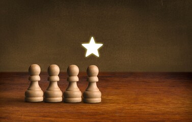 Hand holding a golden star and wooden chess pices