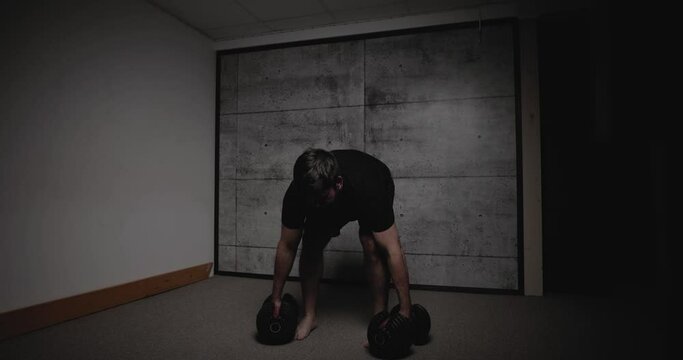 Dumbbell Romanian deadlift, cinematic lighting, white man dressed in black gym attire.