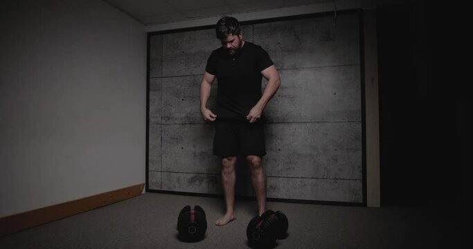 Dumbbell bent over row, cinematic lighting, white man dressed in black gym attire.
