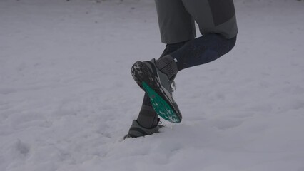 Unknown male jogging in winter in running shoes on snow. Running in all kinds of conditions. Legs of jogger in freezing snowy weather. Every day to run and exercise, no matter what season. 