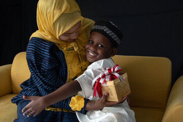 Close relationship between African Muslim mother and son in traditional clothes, boy gives a...