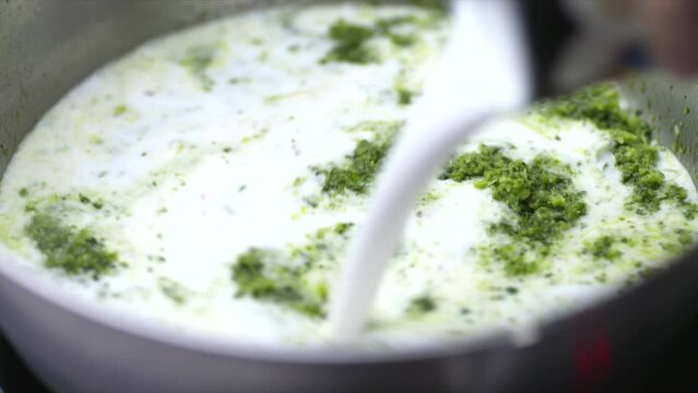 Coconut milk poured into Thai green curry paste. HD Image of saucepan of spicy foos cooking. Healthy Plant-Based Vegan food.