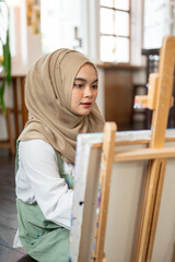 A talented Asian-Muslim female artist is focusing on creating her artwork, painting on canvas.
