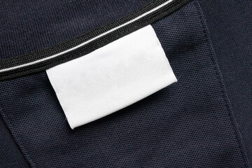 Blank white laundry care clothes label on black shirt fabric texture background