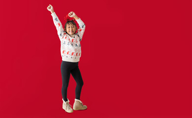 Cheerful young Asian girl wearing a Christmas sweater with reindeer horns, Happy smiling...