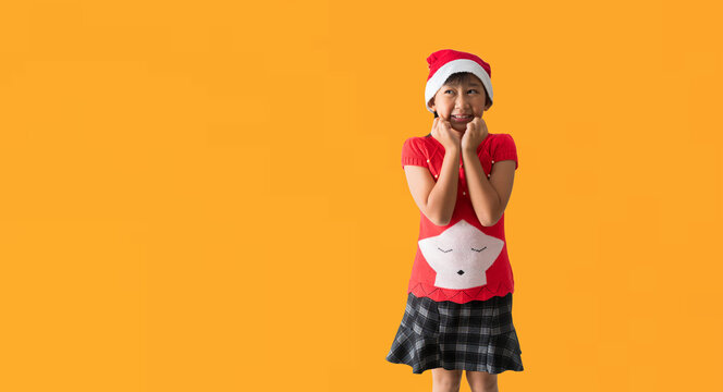 Christmas girl in santa hat and Looking surprise posing, isolated on yellow background