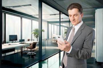 Naklejka na ściany i meble Smiling mature businessman posing in office with phone, AI generated image