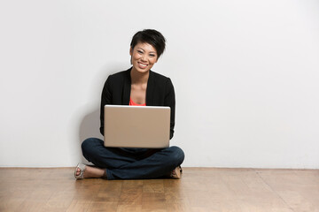 Happy young Chinese woman sitting with a laptop