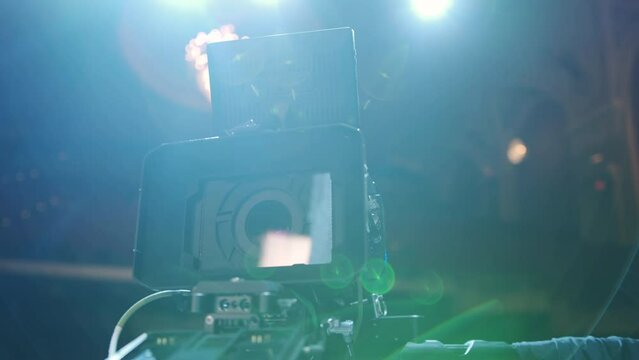 Professional digital cinema camera with set of light hanging in studio background and stage light