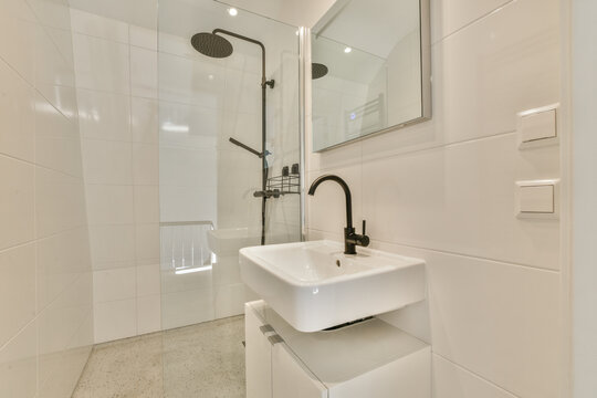 a white bathroom with a sink and mirror on the wall, in front of a walk - in shower stall