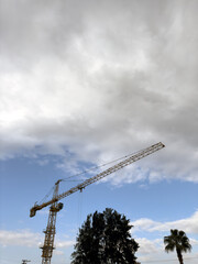 Background of a crane with an upward view against a cloudy sky, a symbol of progress and ambition, portrait.