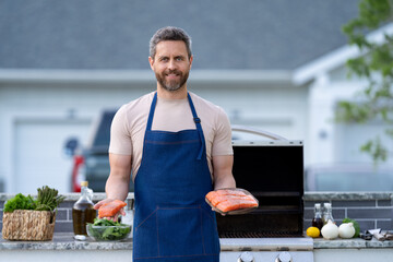 glad bbq man with salmon fish. bbq man with salmon fish outdoor. bbq man with salmon fish in apron
