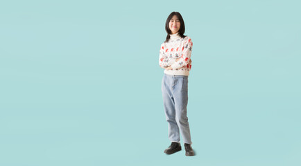 Happy smiling asian teenager girl standing posing with arms crossed, Wearing a Christmas sweater...