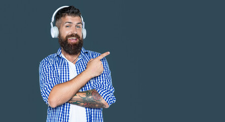 happy bearded man listen to music pointing finger on headphones