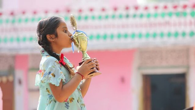 Cute little girl child holding and kissing her winning trophy