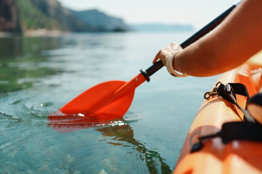 Kayak paddle sea vacation. Person paddles with orange paddle oar on kayak in sea. Leisure active lifestyle recreation activity rest tourism travel